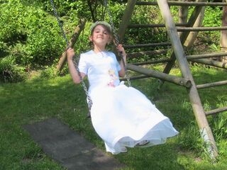 Erstkomunionkind auf der Schaukel